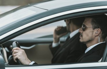 bodyguards with portable radio and security earpiece sitting in a car